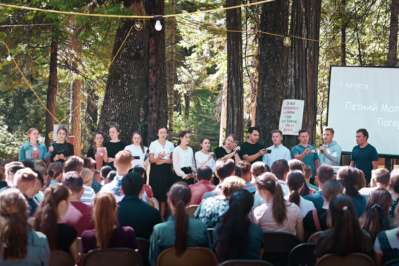 Campers singing together at an outdoor daytime worship service
