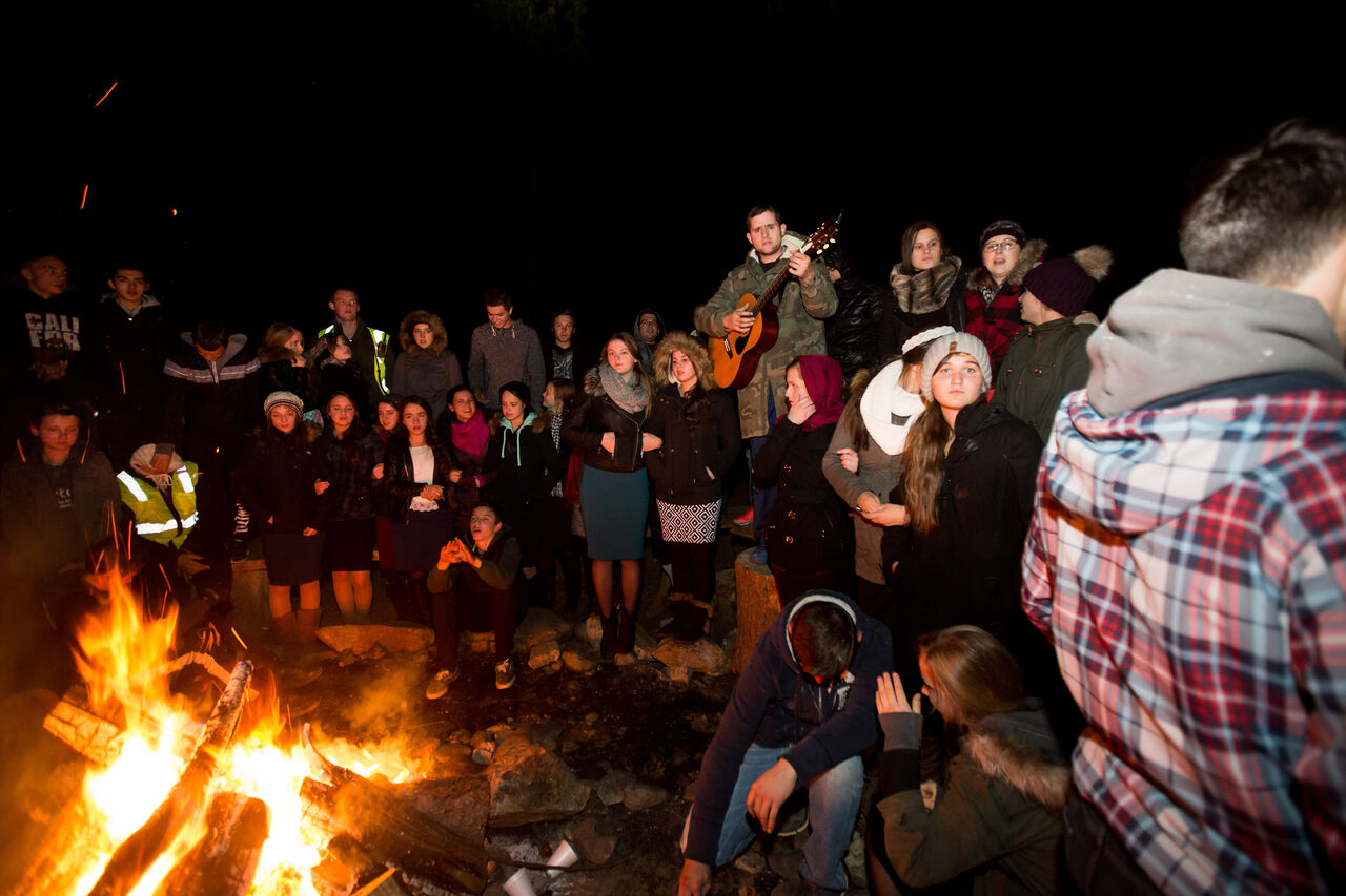 Campers singing around a campfire with a guitar